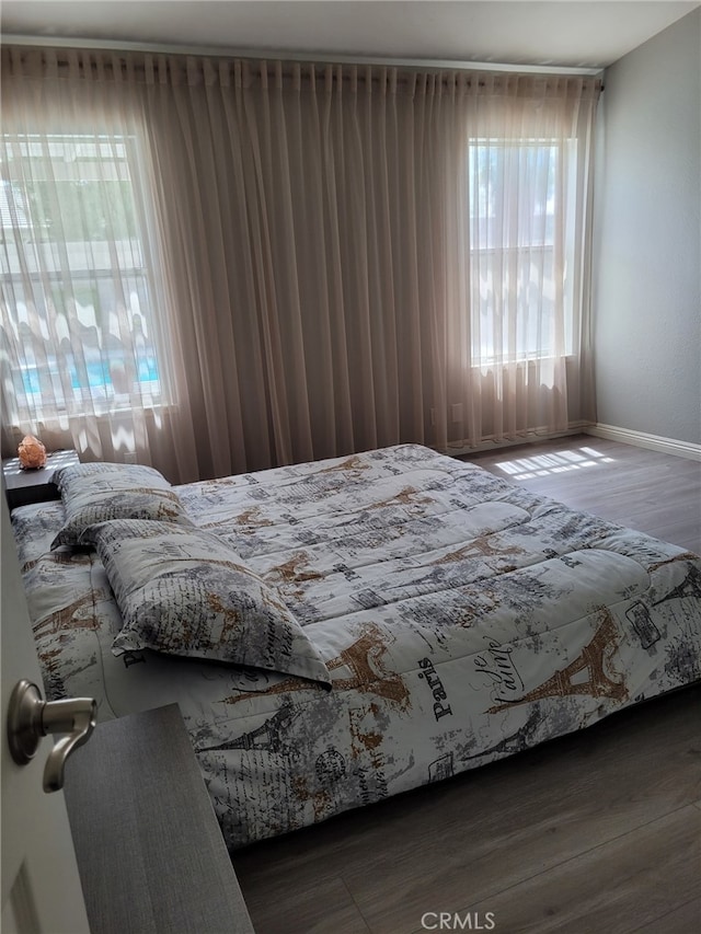 bedroom with dark wood-type flooring and multiple windows