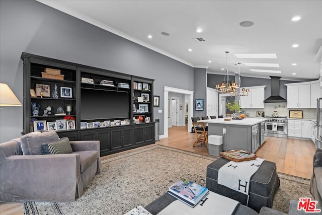 living room with ornamental molding, an inviting chandelier, and vaulted ceiling with skylight