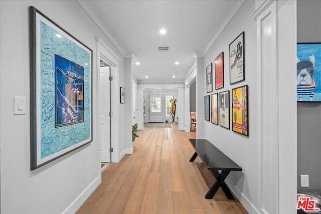 corridor with light hardwood / wood-style flooring, crown molding, and ornate columns