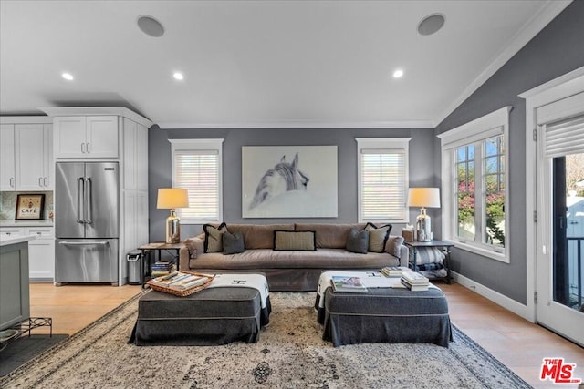 living room with crown molding, light hardwood / wood-style floors, and vaulted ceiling