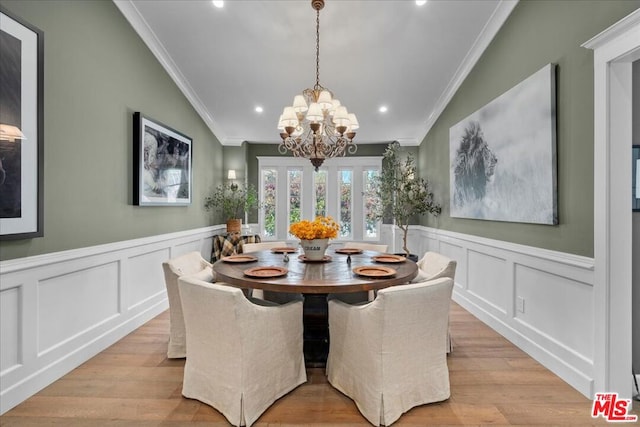 dining area featuring light hardwood / wood-style floors, a chandelier, lofted ceiling, and ornamental molding