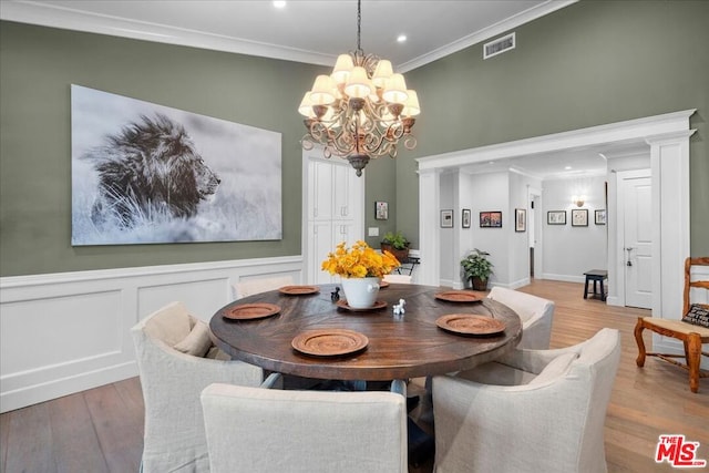 dining area featuring light wood-type flooring, crown molding, and an inviting chandelier