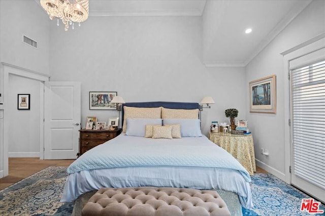 bedroom with hardwood / wood-style flooring, lofted ceiling, ornamental molding, and a notable chandelier