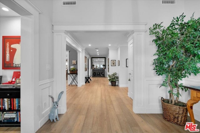 hallway featuring crown molding and light hardwood / wood-style flooring