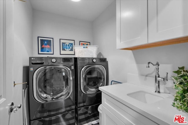 clothes washing area featuring sink, cabinets, and separate washer and dryer