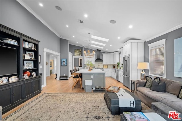 living room with light hardwood / wood-style floors, a wealth of natural light, ornamental molding, and vaulted ceiling