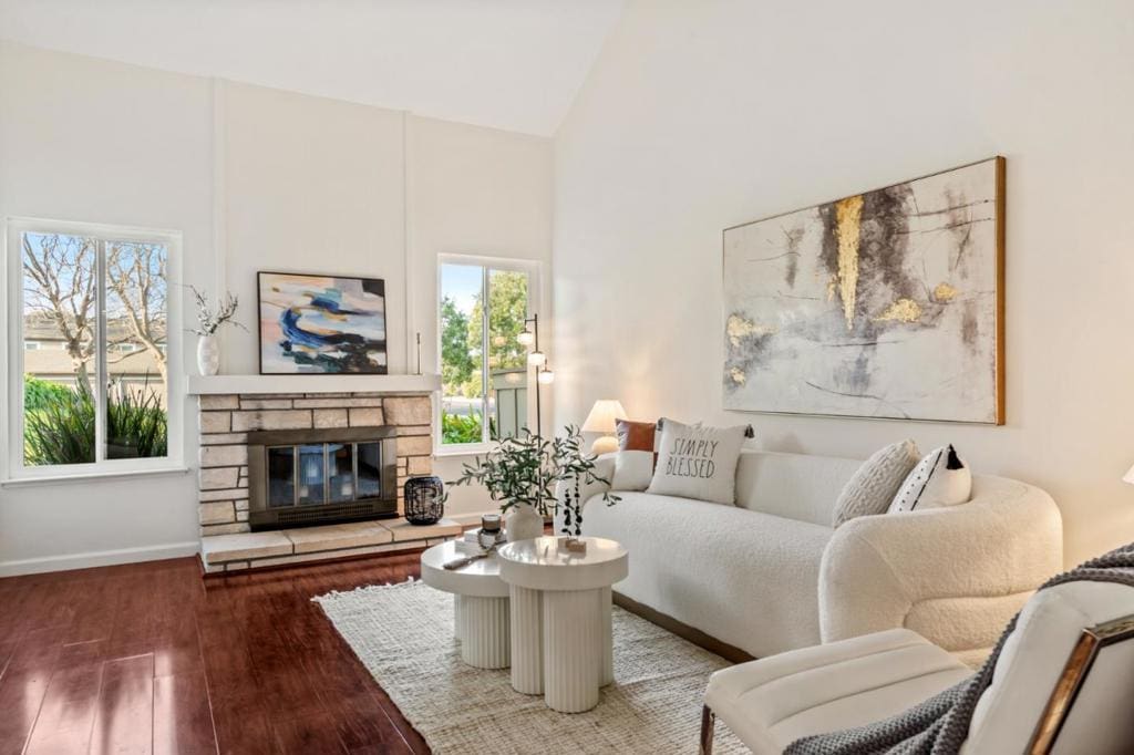 living room with a stone fireplace, wood-type flooring, and high vaulted ceiling