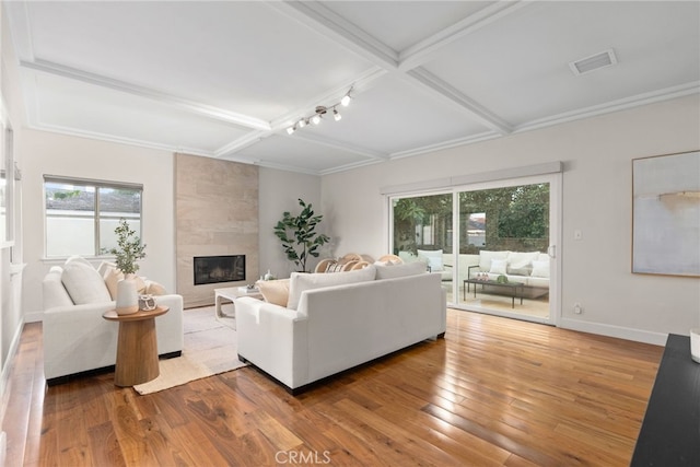 living room with beam ceiling, coffered ceiling, a tile fireplace, and wood-type flooring