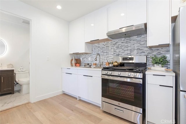 kitchen with light hardwood / wood-style floors, appliances with stainless steel finishes, sink, white cabinets, and backsplash