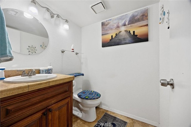 bathroom with toilet, vanity, and tile patterned flooring