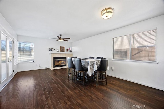 dining area featuring ceiling fan, dark hardwood / wood-style floors, and a tiled fireplace