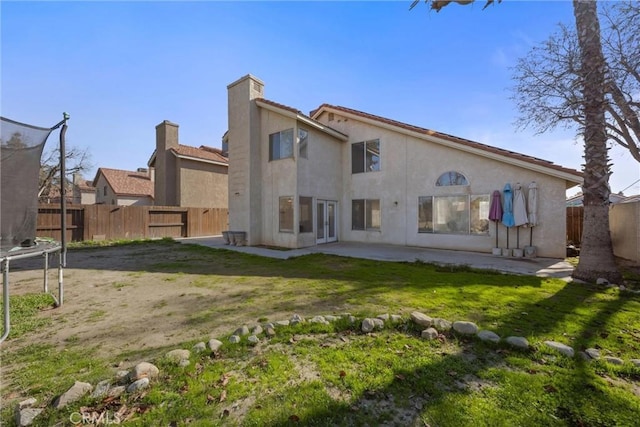 back of house with a yard, a patio, and a trampoline