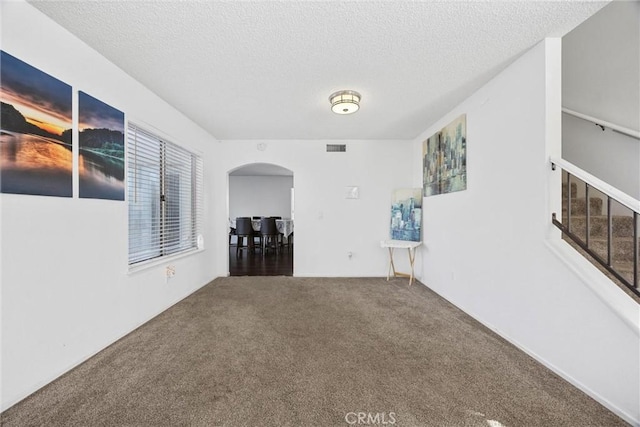 unfurnished room with carpet and a textured ceiling