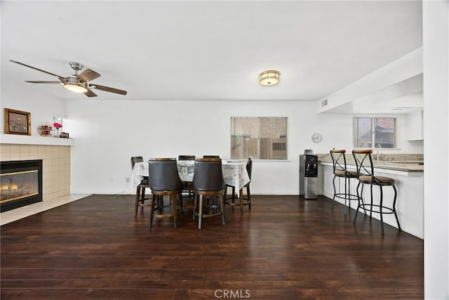 dining space with sink, ceiling fan, dark hardwood / wood-style flooring, and a fireplace