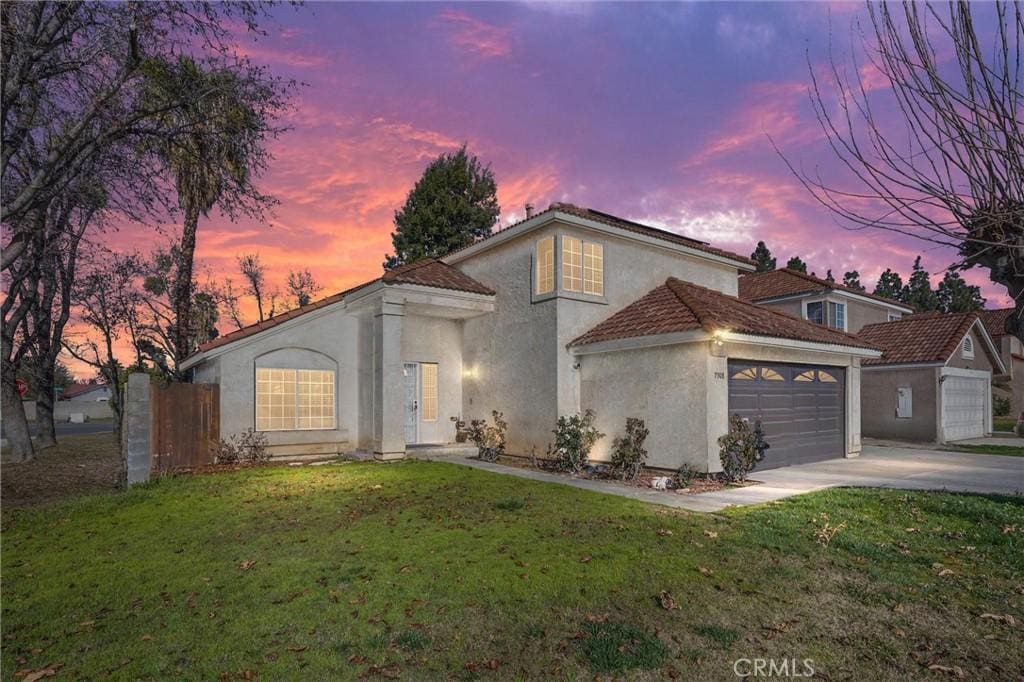 mediterranean / spanish home featuring a garage and a yard