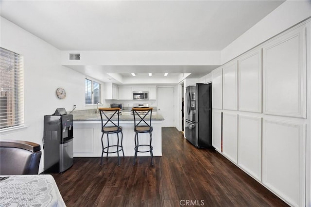 kitchen featuring kitchen peninsula, a breakfast bar area, white cabinetry, and stainless steel appliances