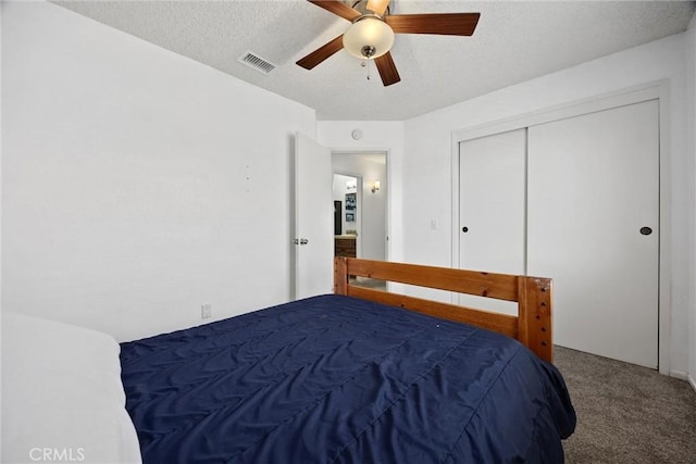 carpeted bedroom with a textured ceiling, a closet, and ceiling fan