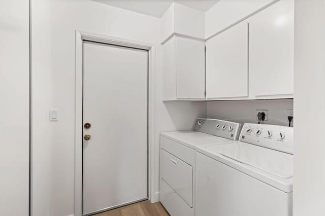 clothes washing area with cabinets, washer and clothes dryer, and light hardwood / wood-style floors