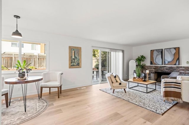 living room with light wood-type flooring and a brick fireplace