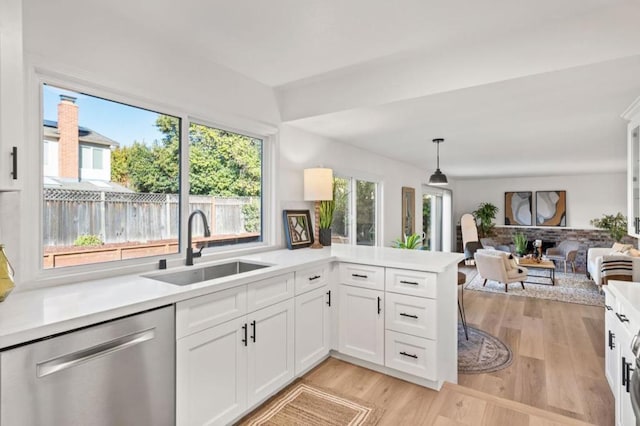 kitchen featuring white cabinetry, stainless steel dishwasher, sink, kitchen peninsula, and pendant lighting