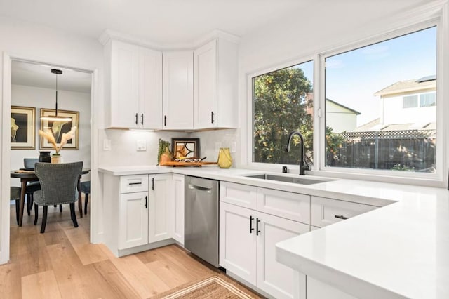 kitchen featuring pendant lighting, sink, white cabinetry, and light wood-type flooring