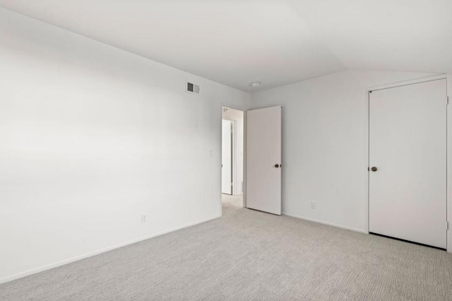 carpeted empty room featuring vaulted ceiling