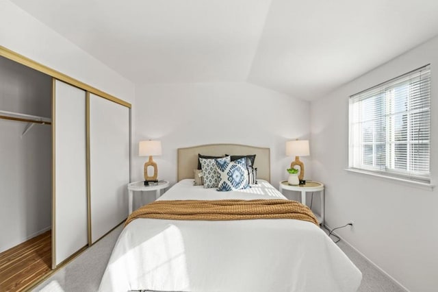 carpeted bedroom with a closet and lofted ceiling