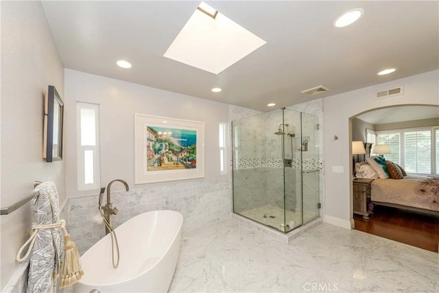 bathroom featuring tile walls, a skylight, and independent shower and bath