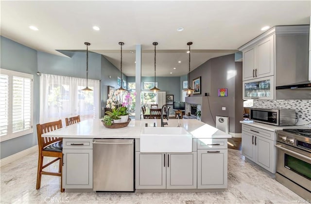 kitchen with a kitchen island with sink, sink, gray cabinets, and appliances with stainless steel finishes