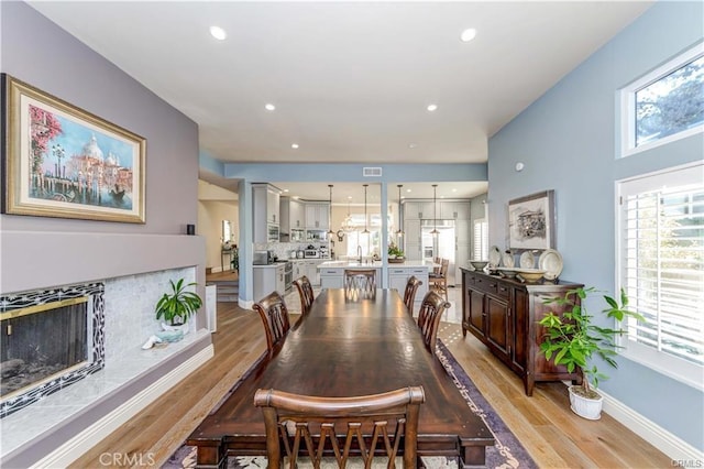 dining area featuring sink, a fireplace, and light hardwood / wood-style flooring