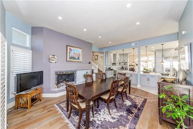 dining room featuring a tile fireplace and light hardwood / wood-style flooring