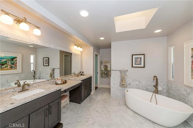 bathroom with vanity, tile walls, a bathtub, and a skylight