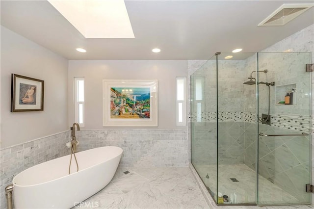 bathroom featuring tile walls, a skylight, and plus walk in shower