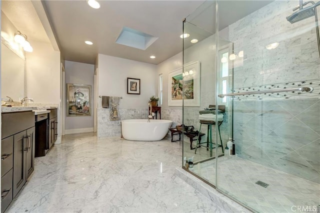 bathroom featuring vanity, separate shower and tub, tile walls, and a skylight