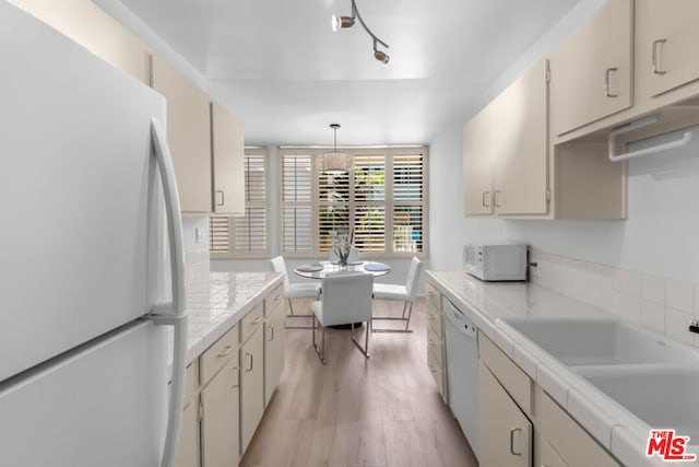 kitchen featuring white appliances, light hardwood / wood-style floors, tile counters, sink, and decorative light fixtures