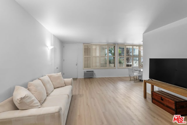 living room featuring light hardwood / wood-style flooring and a wall unit AC