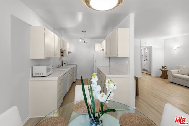 kitchen with white cabinetry, white appliances, and light hardwood / wood-style floors