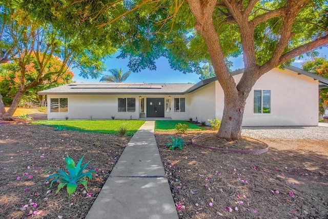 ranch-style home featuring solar panels and a front lawn