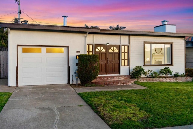 view of front of home with a garage and a lawn