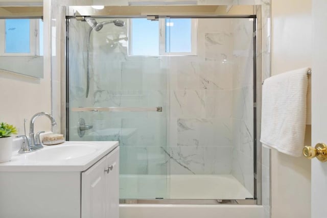 bathroom featuring bath / shower combo with glass door and vanity