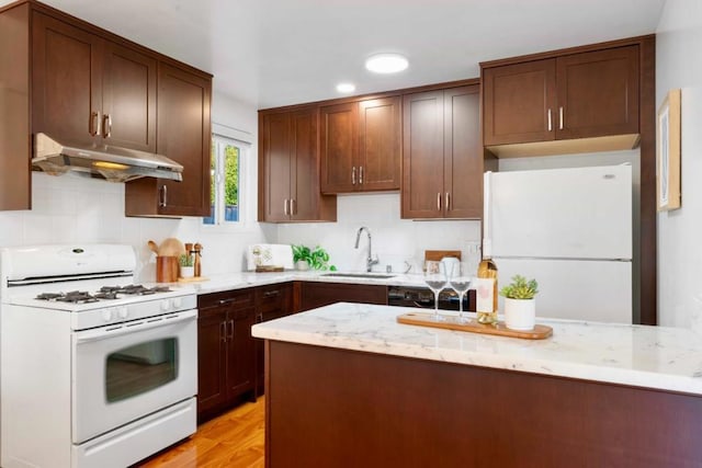 kitchen with sink, white appliances, light hardwood / wood-style flooring, and light stone countertops