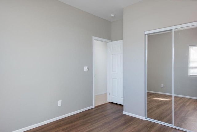 unfurnished bedroom with dark hardwood / wood-style floors and a closet