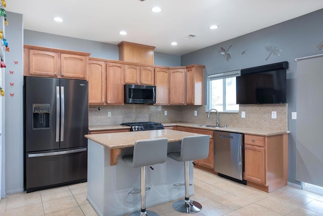 kitchen featuring appliances with stainless steel finishes, sink, light stone countertops, light tile patterned flooring, and a kitchen island