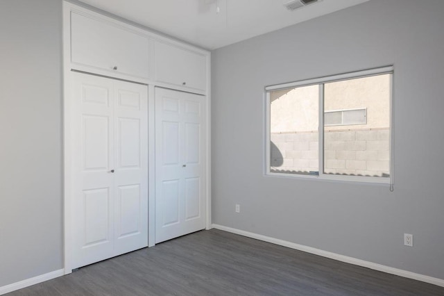 unfurnished bedroom featuring dark wood-type flooring and a closet