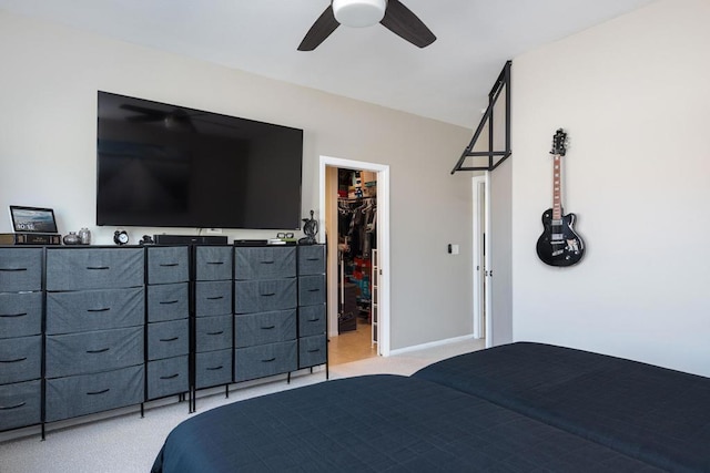 bedroom with a walk in closet, ceiling fan, light carpet, and a closet