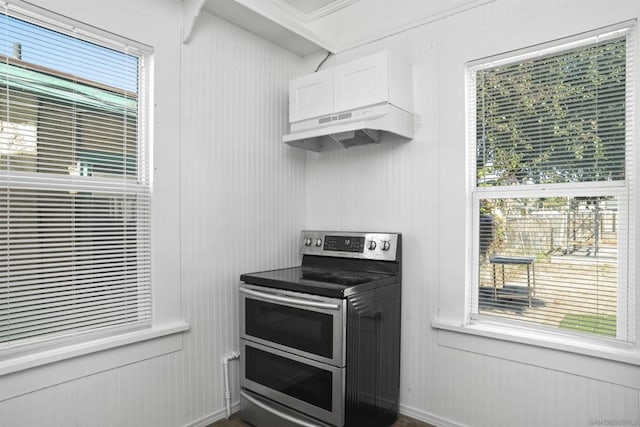 kitchen with plenty of natural light, range with two ovens, white cabinetry, and ornamental molding