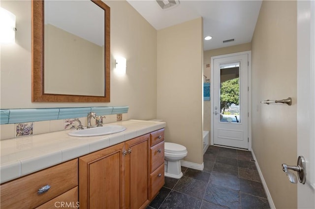 bathroom with vanity, toilet, and backsplash