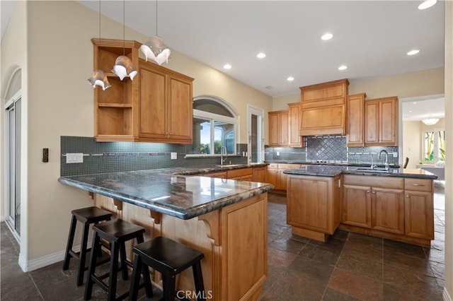 kitchen featuring decorative backsplash, sink, kitchen peninsula, pendant lighting, and a breakfast bar area