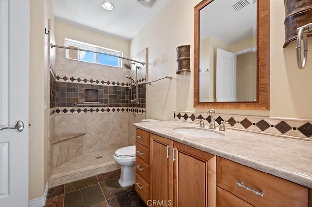 bathroom featuring tiled shower, toilet, and vanity