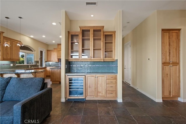 kitchen with decorative backsplash, sink, kitchen peninsula, pendant lighting, and beverage cooler